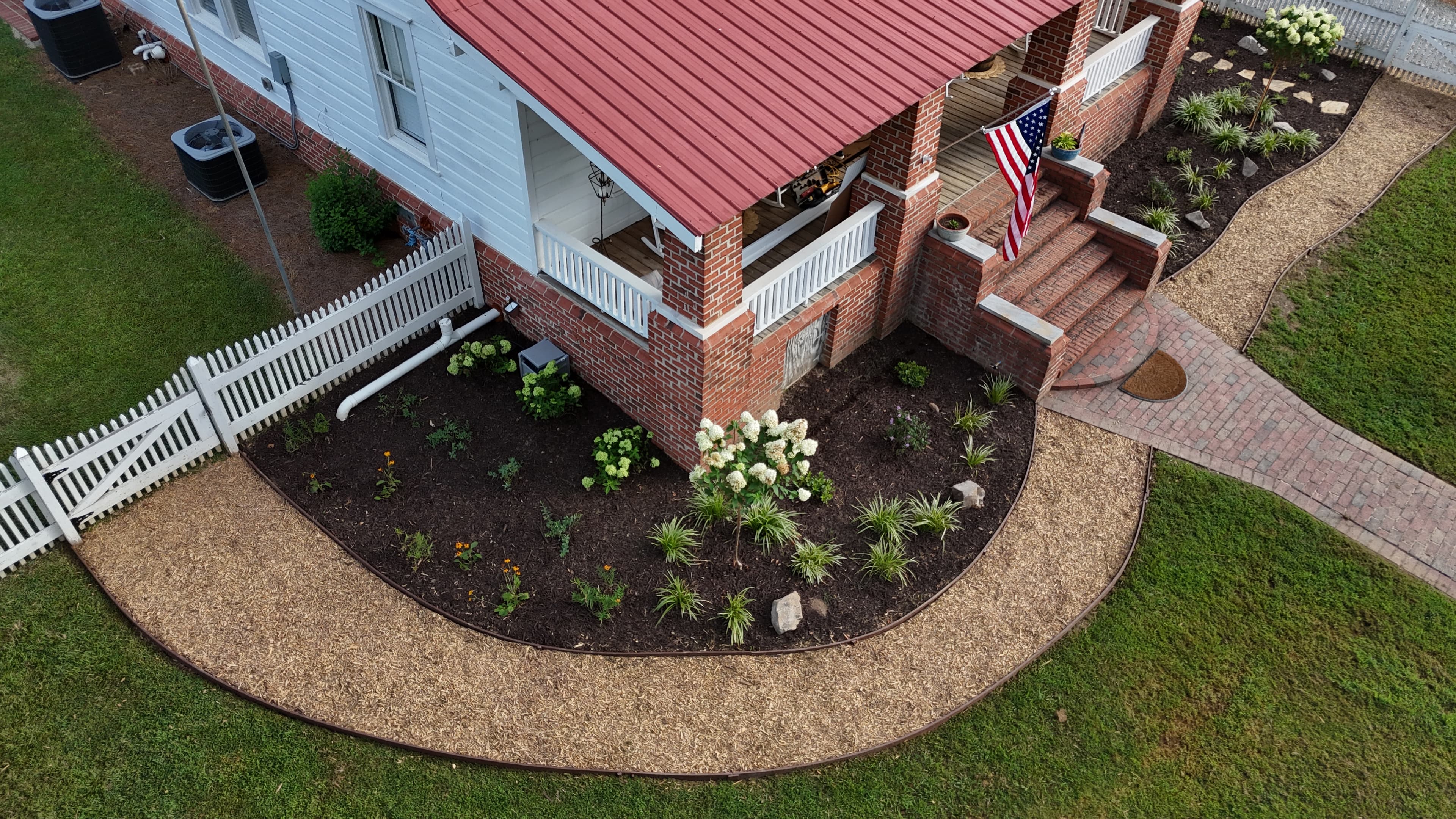 Aerial view of a white house with a red roof and a curved landscaped garden.